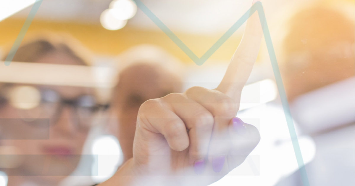 Nainen osoittaa työtovereilleen sormellaan kaaviota